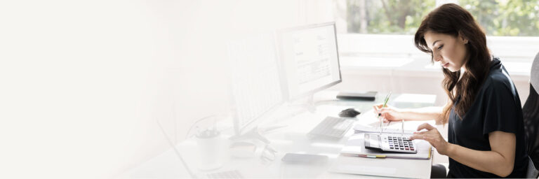 Kobieta siedząca przy biurku licząca na kalkulatorze