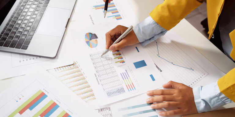 Osoba wskazująca długopisem tabelkę z danymi